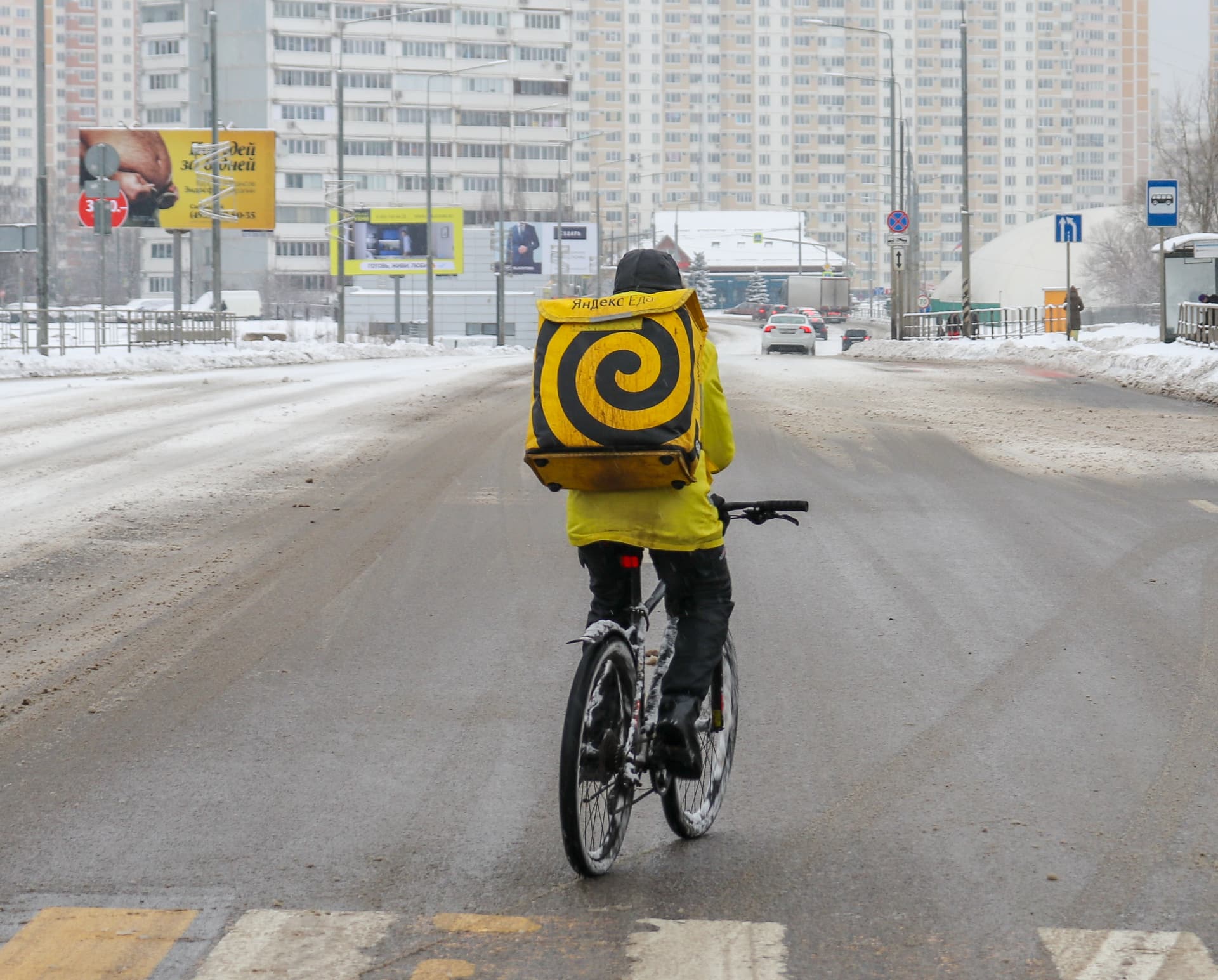A Yandex Eda courier on a snowy street in a residential district, January 2021. Photo: Stolbovsky
